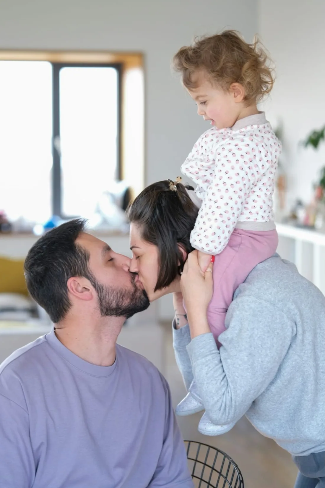 Pareja celebrando con su hija pequeña sobre los hombros de la madre